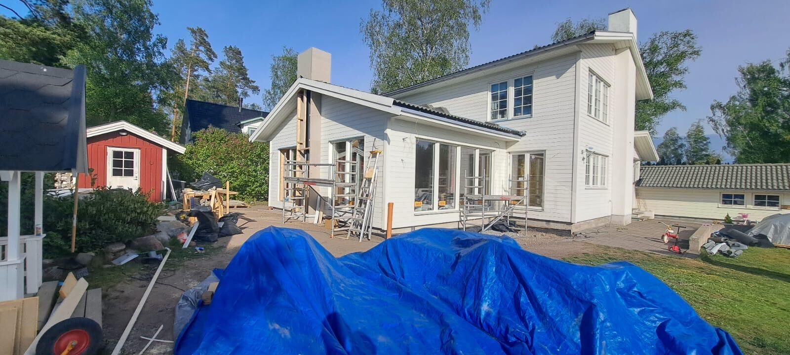 Färdig tillbyggnad med vit träfasad och stora fönsterpartier