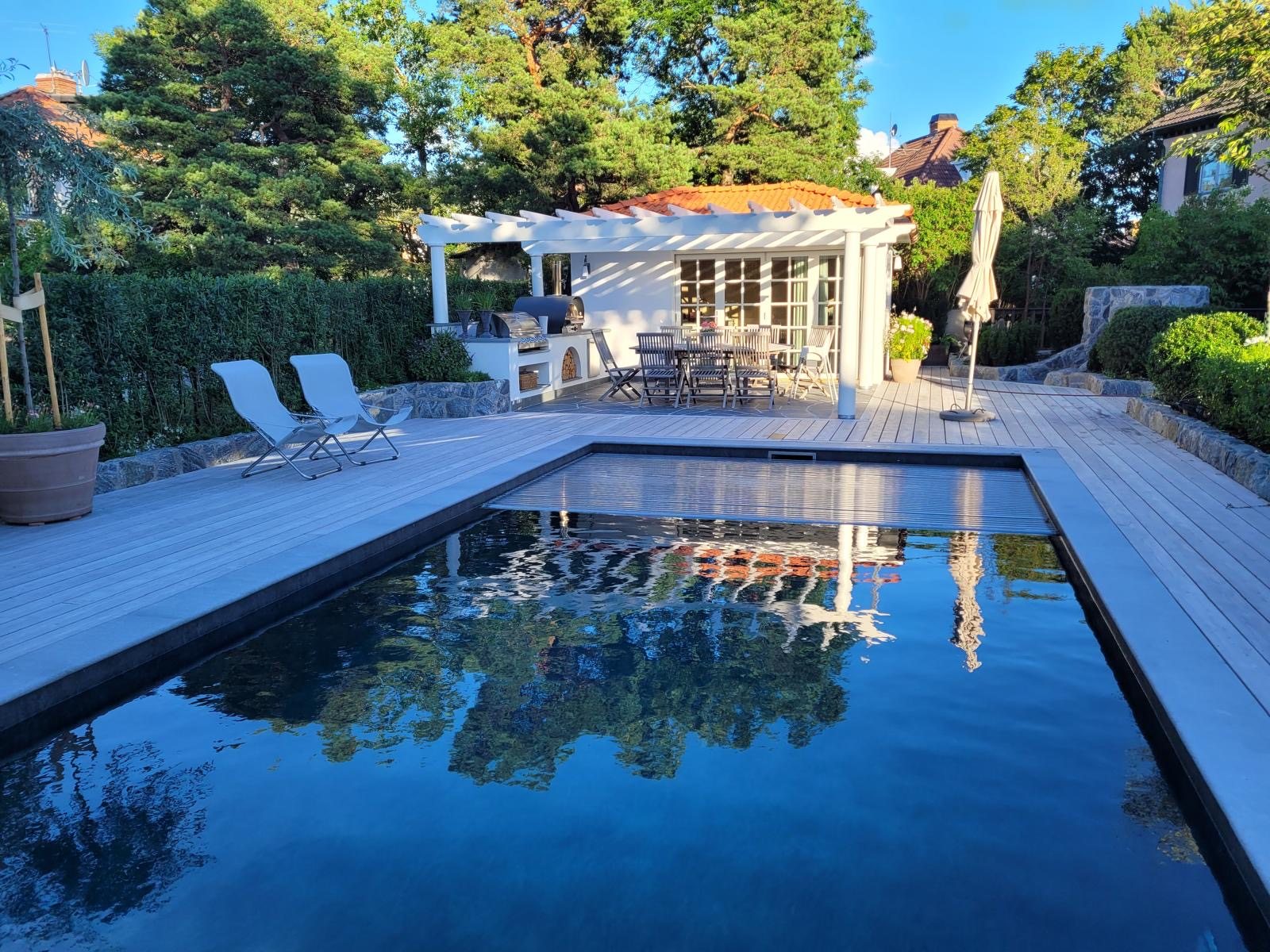 Färdig poolmiljö med trädäck och pergola
